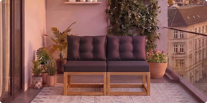 Διθέσιος αρθρωτός ξύλινος καναπές με σκούρα γκρι μαξιλάρια σε μπαλκόνι με γλάστρες και θέα στην πόλη στο φόντο